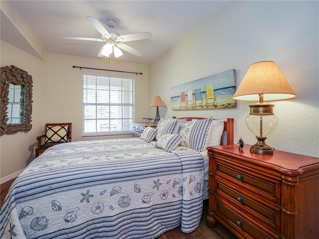 A bedroom features a bed with a seashell-patterned quilt, a wooden nightstand, and a ceiling fan — 2288 57th Circle # 2288, Vero Beach FL 32966, VERO BEACH, FL