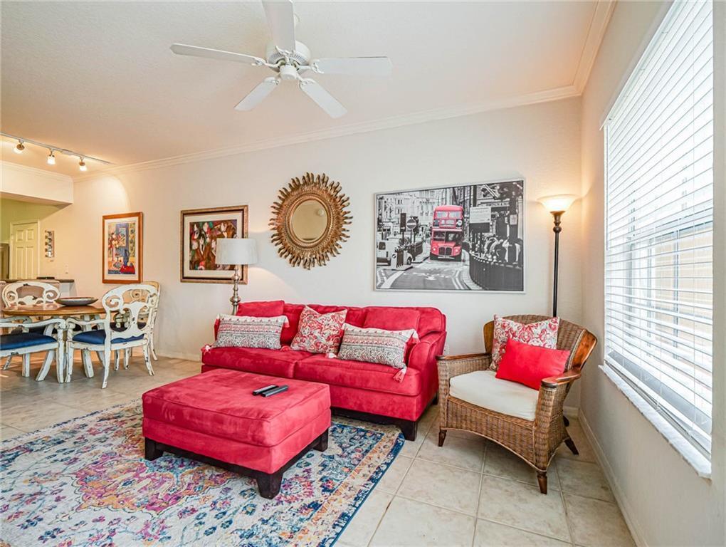 A living room features a red sofa, matching ottoman, wicker chair, and a patterned area rug — 2288 57th Circle # 2288, Vero Beach FL 32966, VERO BEACH, FL