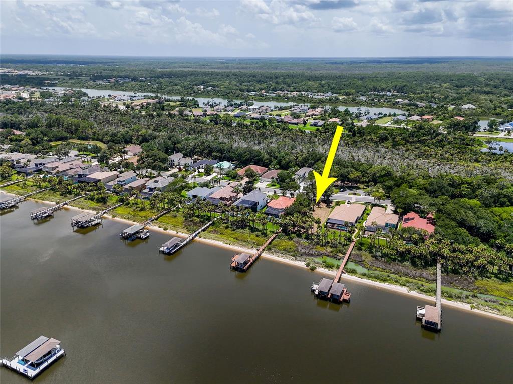 An aerial view shows a vacant waterfront lot outlined in yellow next to residential homes — 81 S RIVERWALK DRIVE, PALM COAST, FL