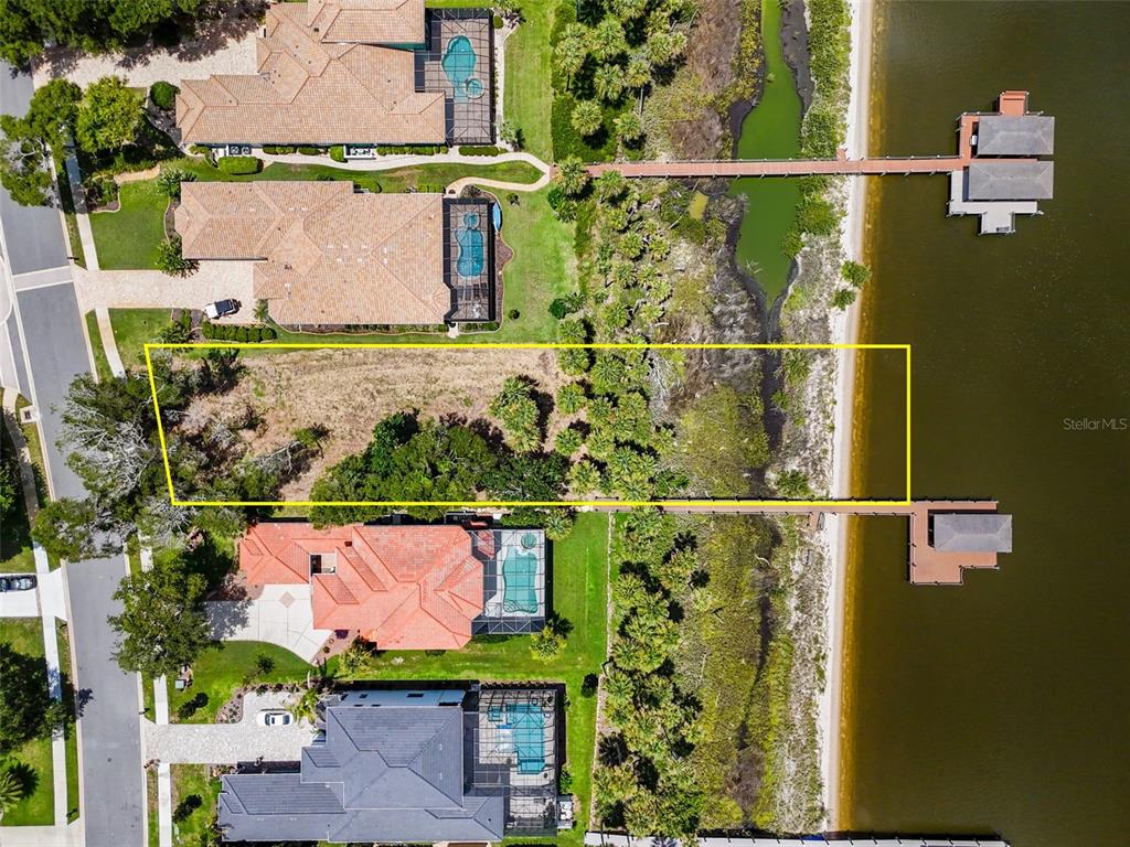 An aerial view shows a vacant waterfront lot situated between two existing residential properties — 81 S RIVERWALK DRIVE, PALM COAST, FL