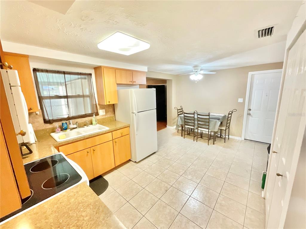A kitchen with light wood cabinets, a white refrigerator, and a dining area with tile floors — 4750 GASLIGHT AVENUE, HOLIDAY, FL