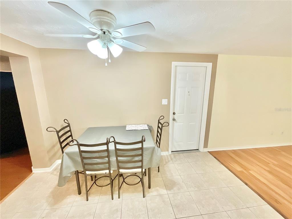 A dining area features a table with four chairs, a ceiling fan, and tile flooring — 4750 GASLIGHT AVENUE, HOLIDAY, FL