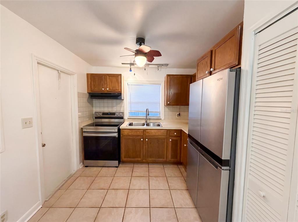 A kitchen features wood cabinets, stainless steel appliances, a double sink, and tiled flooring — 626 S 67TH STREET, TAMPA, FL