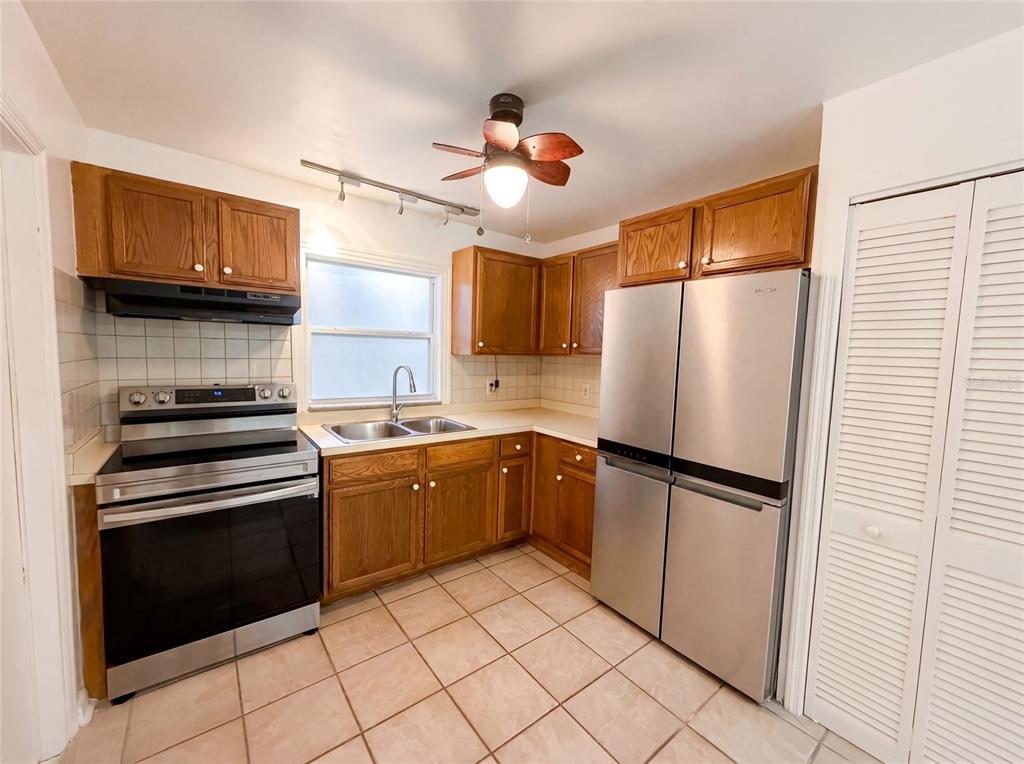 A kitchen features wood cabinets, stainless steel appliances, a tile floor, and a ceiling fan — 626 S 67TH STREET, TAMPA, FL