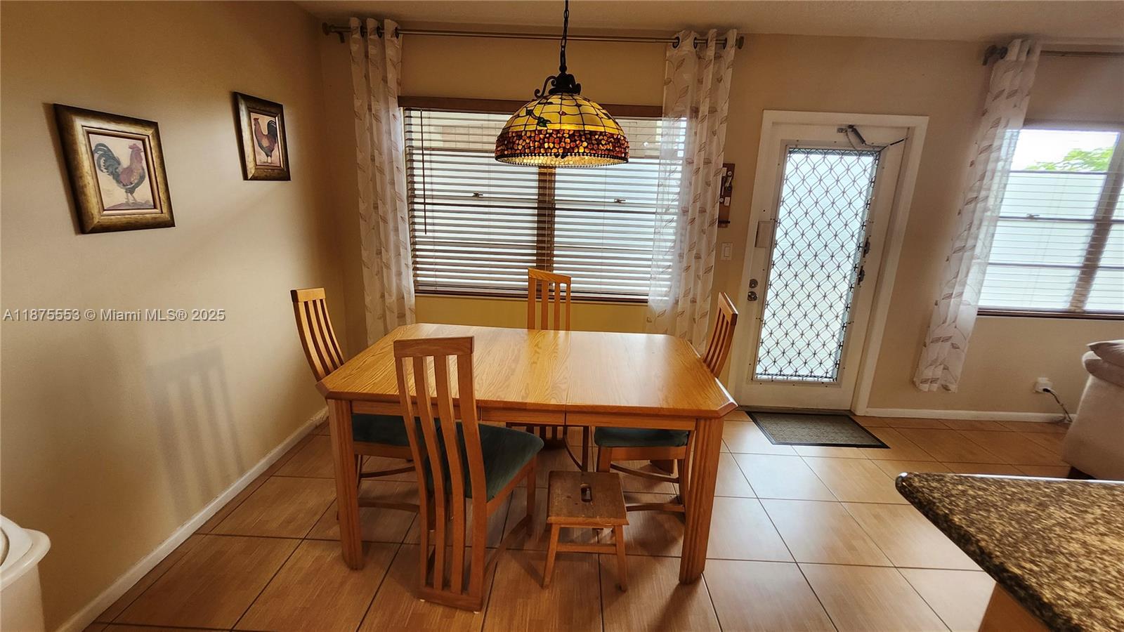 A dining area features a wooden table, four chairs, a stained-glass pendant light, and tile flooring — 3009 Ventnor G # 3009, Deerfield Beach FL 33442, DEERFIELD BEACH, FL