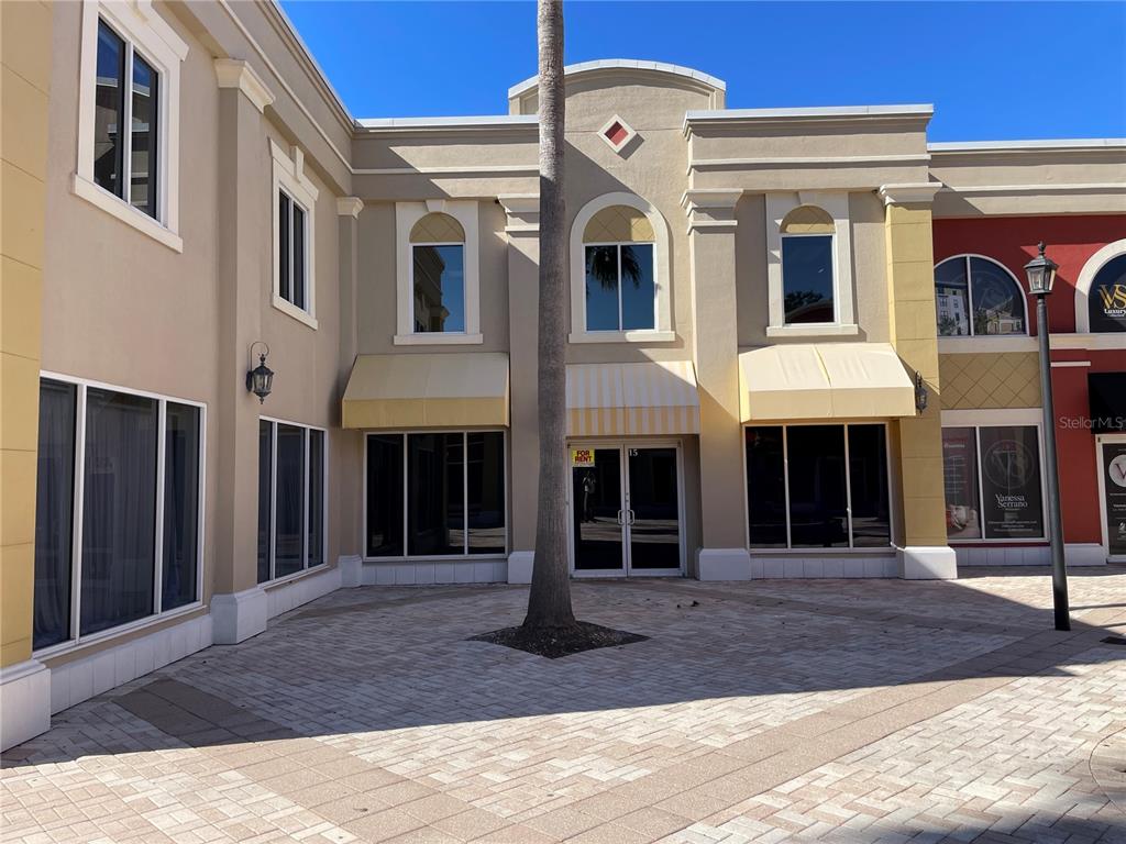 A paved courtyard leads to the entrance of a two-story commercial building with tan stucco — 2151 CONSULATE DRIVE UNIT 15, ORLANDO, FL