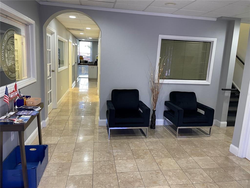 A waiting area features two black armchairs, tile flooring, and an arched hallway entrance — 2151 CONSULATE DRIVE UNIT 15, ORLANDO, FL