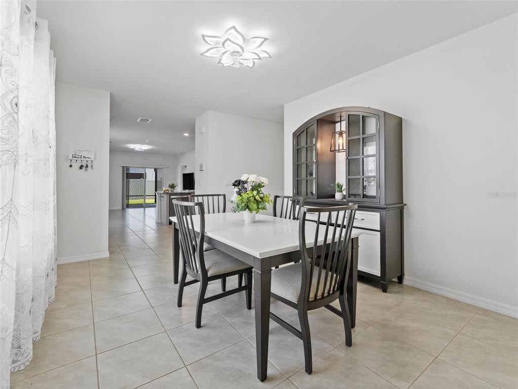 A dining room features a white table, dark chairs, and a matching hutch on tile flooring — 5782 HOLLINGWORTH TRAIL, WESLEY CHAPEL, FL