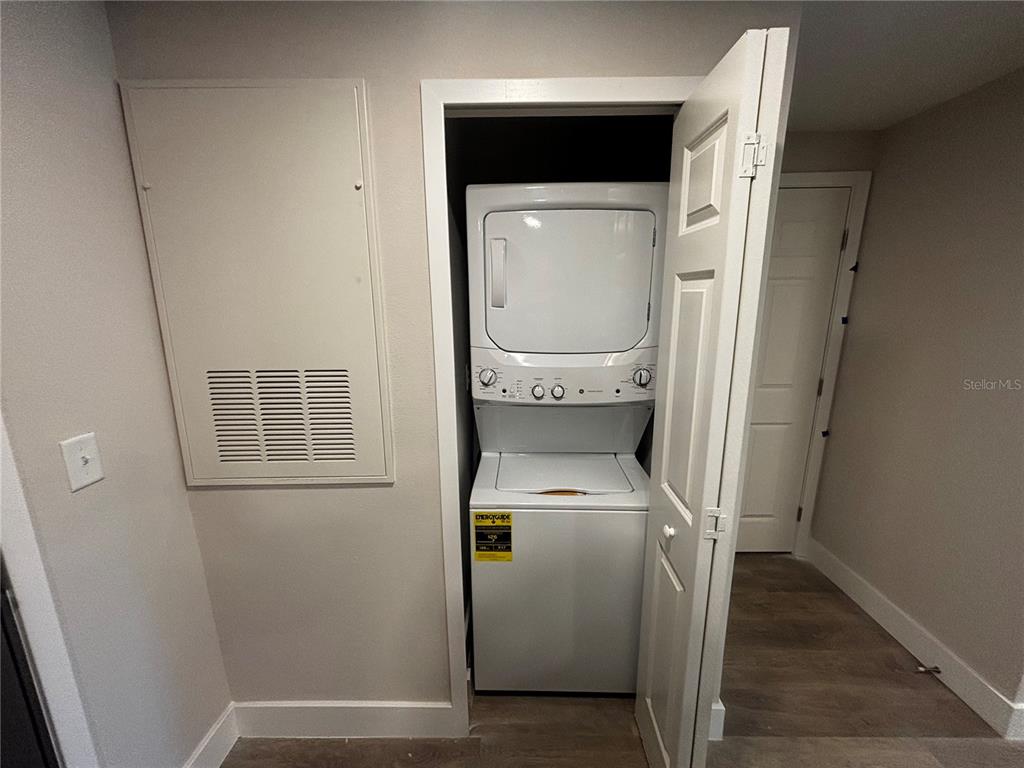 A laundry closet contains a stacked washer and dryer unit next to a wall vent — 4424 S TEXAS AVENUE UNIT 1-205, ORLANDO, FL