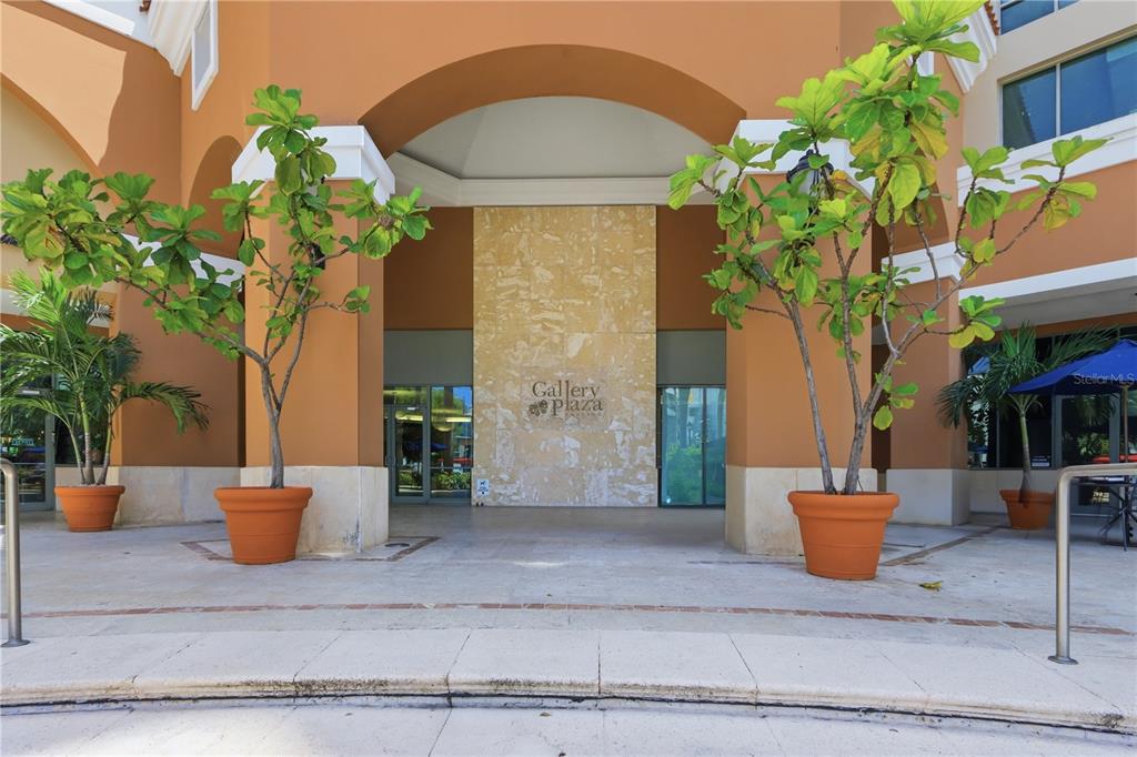 The exterior entrance of a building features a stone facade, potted trees, and arched columns — 103 DE DIEGO UNIT 903, SAN JUAN, PR