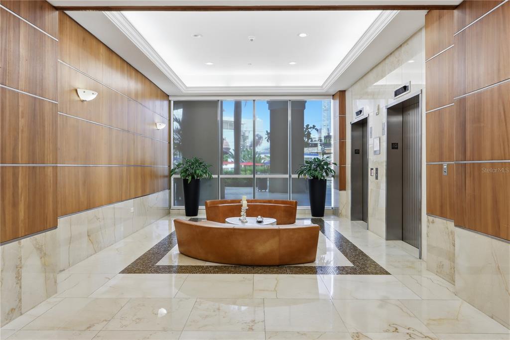 A modern lobby features wood-paneled walls, marble floors, two elevators, and curved leather seating — 103 DE DIEGO UNIT 903, SAN JUAN, PR