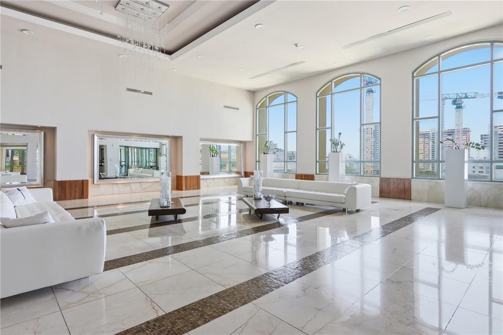 A spacious, modern lobby features white sofas, marble floors, and large arched windows overlooking city construction — 103 DE DIEGO UNIT 903, SAN JUAN, PR
