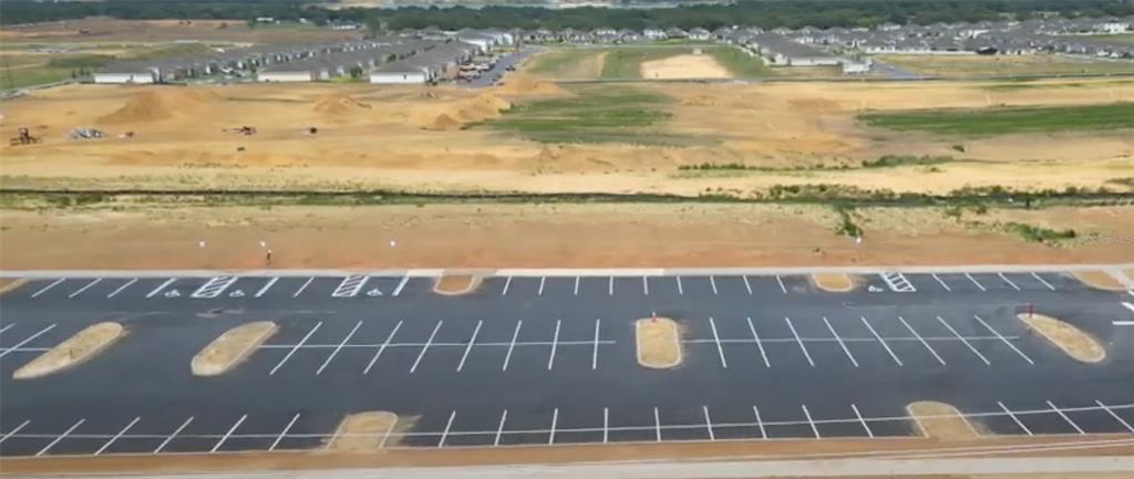 An aerial view shows a newly paved parking lot adjacent to a large, undeveloped construction site — 1295 S 30TH STREET, HAINES CITY, FL