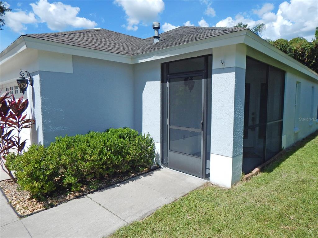A view of a house exterior featuring a screened-in porch and a concrete walkway — 5827 MEADOWPARK PLACE, LITHIA, FL