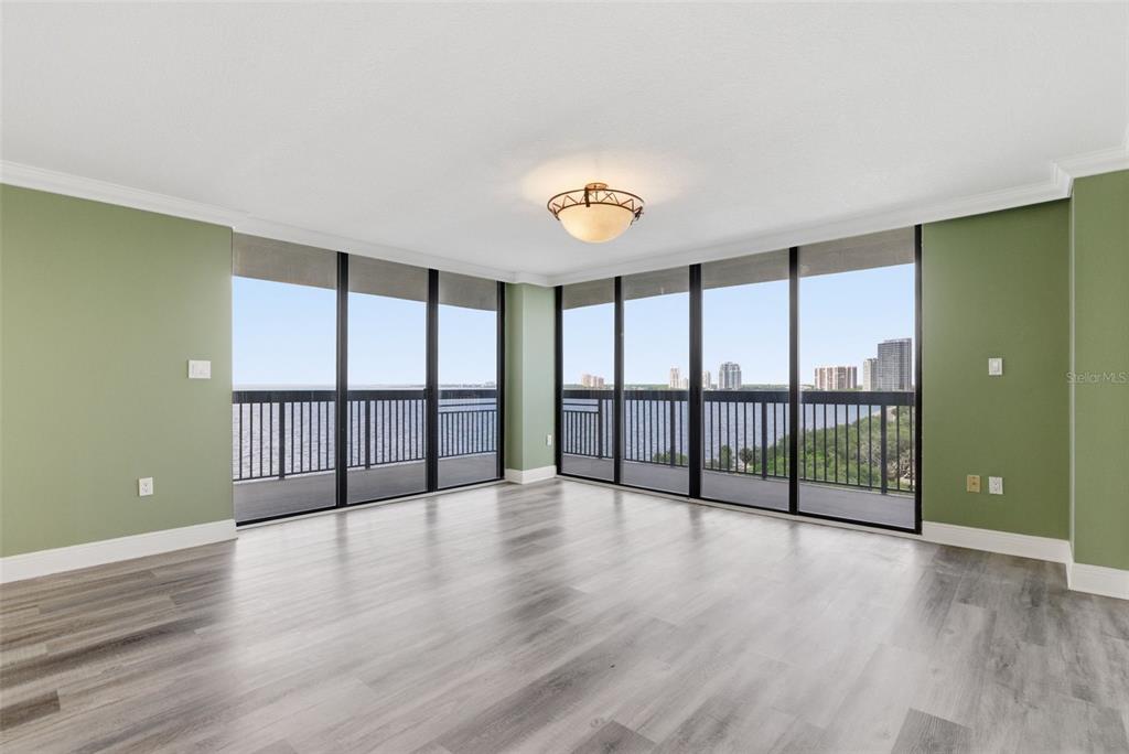 An empty room with green walls, wood-look flooring, and floor-to-ceiling windows overlooking the water — 2413 BAYSHORE BOULEVARD UNIT 1004, TAMPA, FL