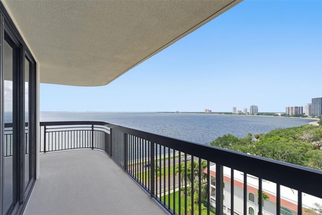 A balcony with a black metal railing overlooks a large body of water and trees — 2413 BAYSHORE BOULEVARD UNIT 1004, TAMPA, FL