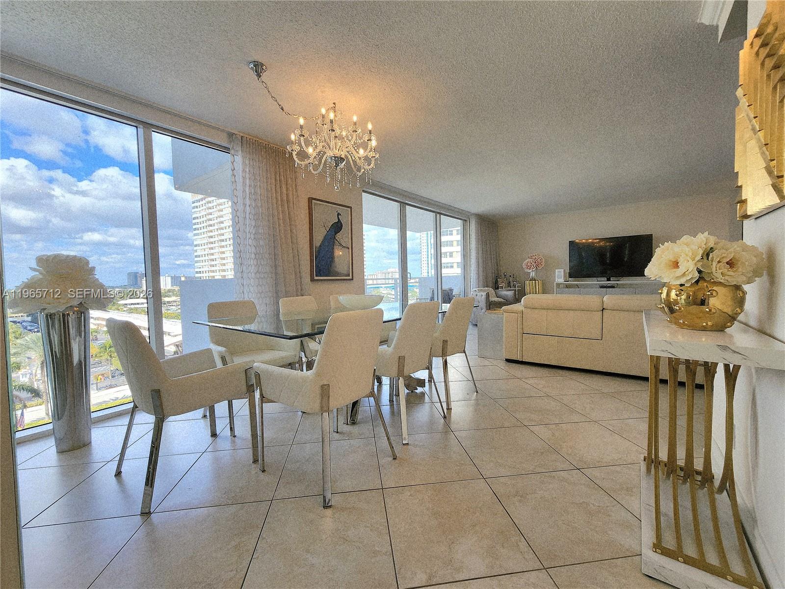 A dining area with a glass table and chairs sits beside a living room — 2030 S Ocean Dr # 626, Hallandale Beach FL 33009, HALLANDALE BEACH, FL