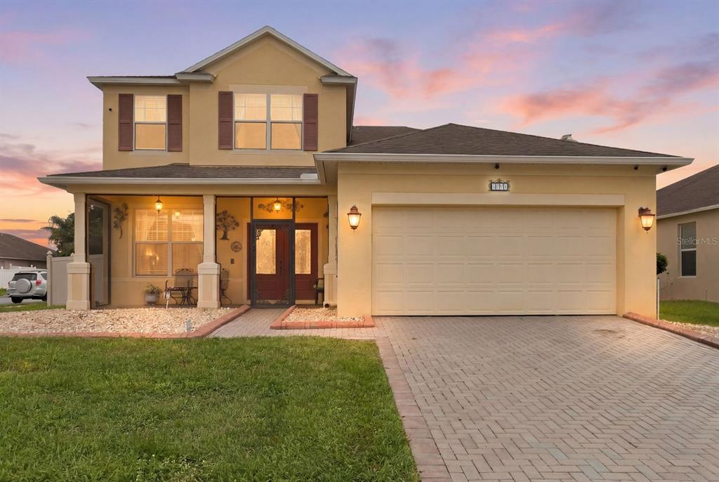 A two-story yellow house with a paved driveway, a two-car garage, and a front porch — 1821 PLANTATION OAK DRIVE, ORLANDO, FL