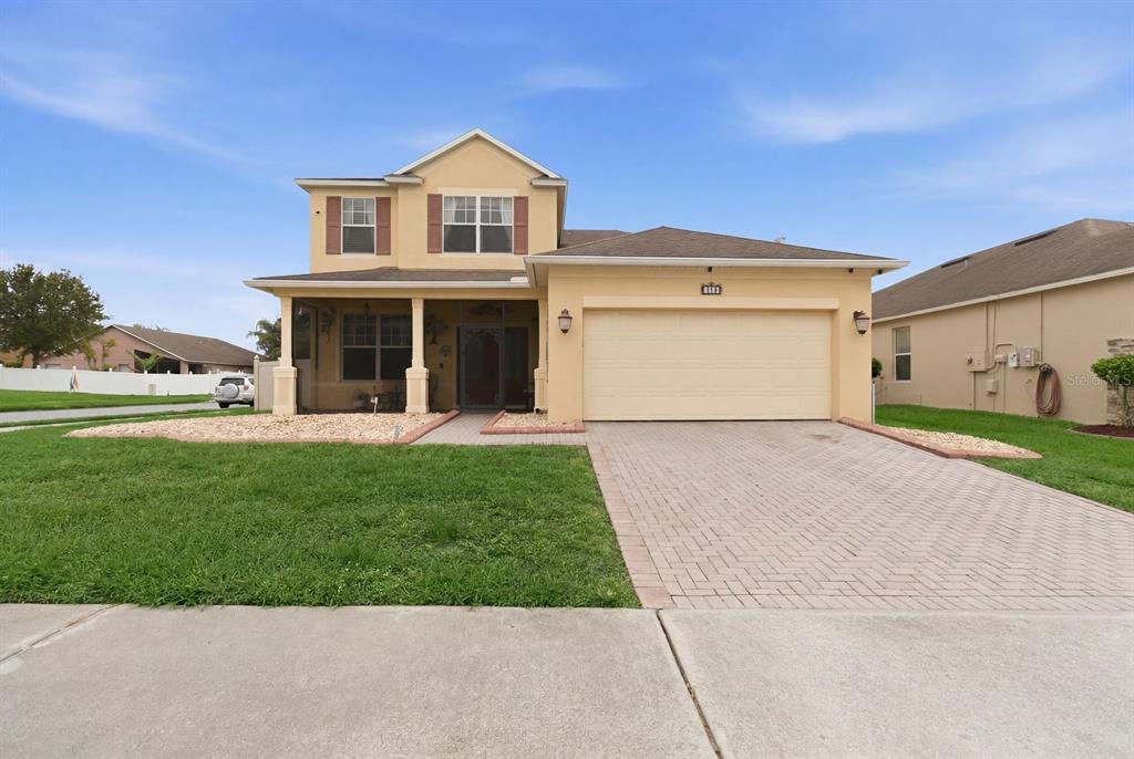 A two-story tan house with a two-car garage and a paved driveway — 1821 PLANTATION OAK DRIVE, ORLANDO, FL