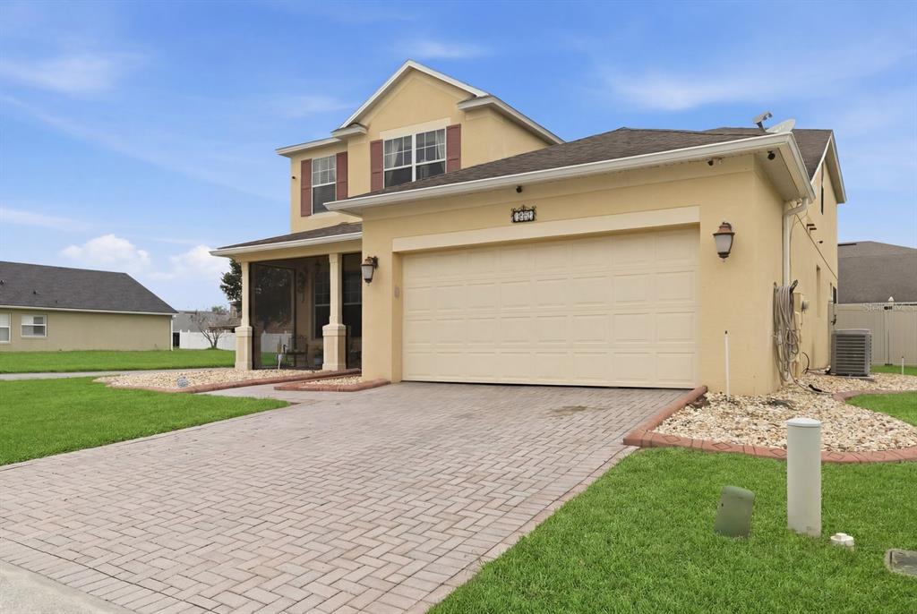 A two-story house with a beige stucco exterior, a two-car garage, and a paved driveway — 1821 PLANTATION OAK DRIVE, ORLANDO, FL