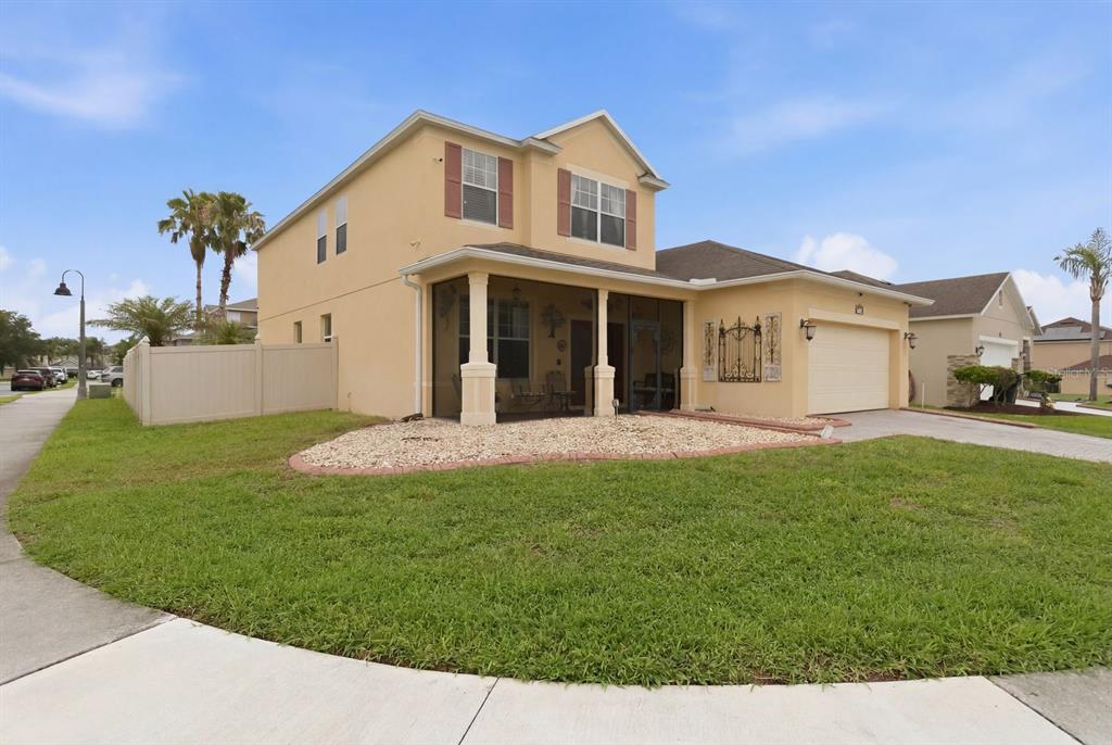A two-story, tan-colored house with a screened-in front porch and an attached garage — 1821 PLANTATION OAK DRIVE, ORLANDO, FL