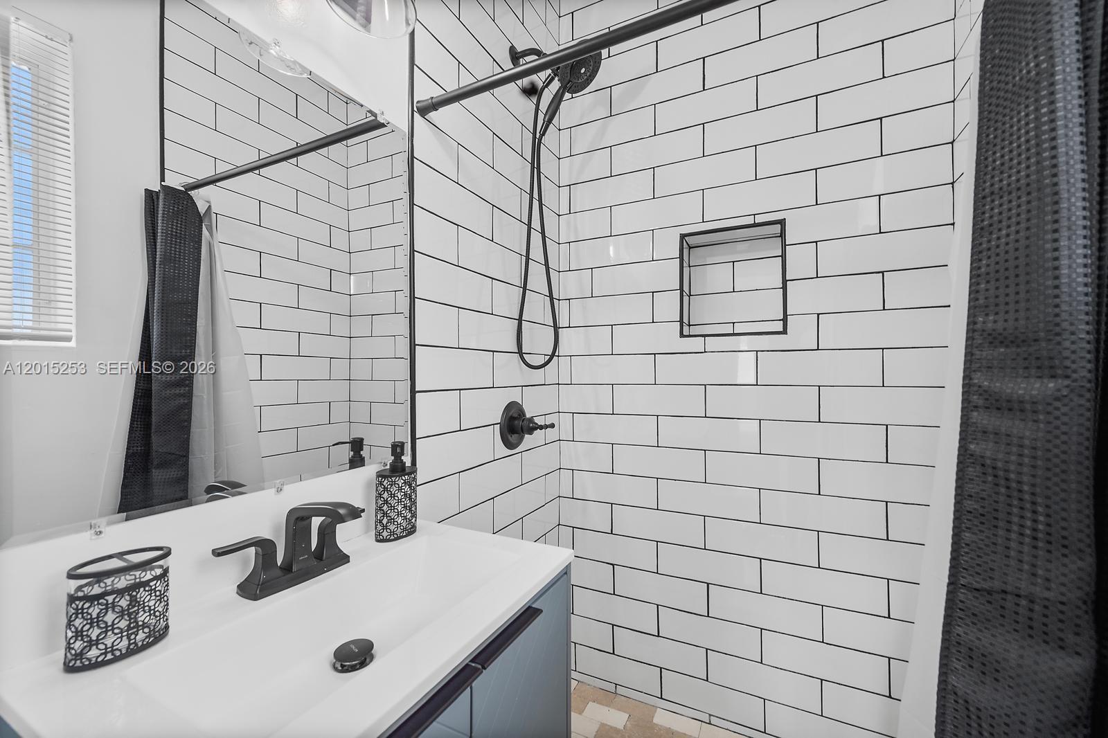 A bathroom features a white subway-tiled shower, a dark vanity, and a black faucet — 301 86th St # 3A, Miami Beach FL 33141, MIAMI BEACH, FL