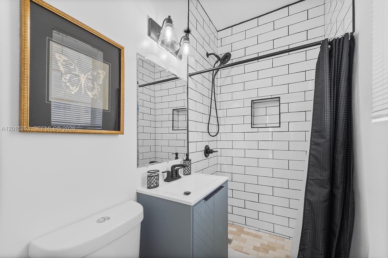 A bathroom features a vanity, toilet, and a shower with white subway tiles — 301 86th St # 3A, Miami Beach FL 33141, MIAMI BEACH, FL