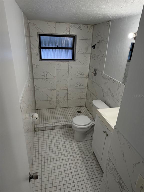 A small bathroom features white marble-look wall tiles, a mosaic tile floor, and a shower — 1923 FRUITLAND PARK CIRCLE, EAGLE LAKE, FL