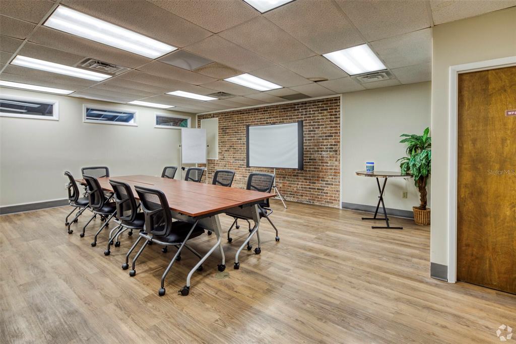A conference room features a long table, rolling chairs, a brick wall, and drop ceilings — 7402 N 56TH ST STREET, TAMPA, FL