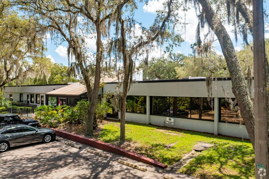 A low-rise commercial building with large windows is surrounded by trees draped in Spanish moss — 7402 N 56TH ST STREET, TAMPA, FL
