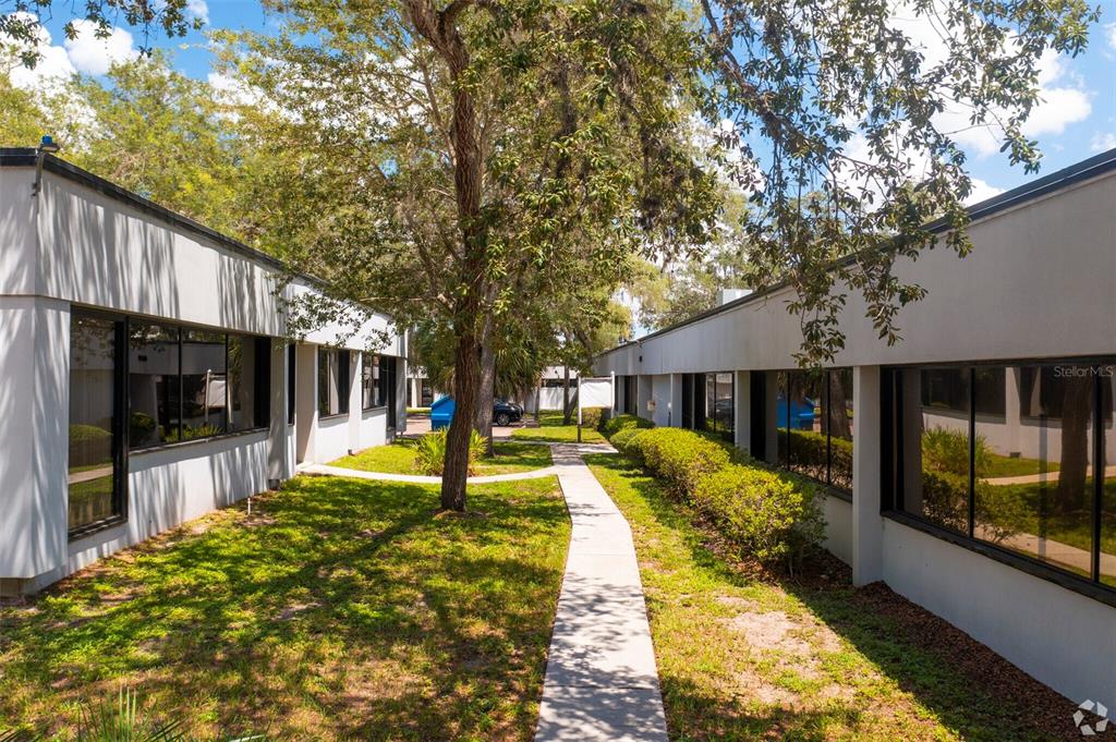 A concrete walkway leads between two single-story office buildings with large windows and landscaping — 7402 N 56TH ST STREET, TAMPA, FL