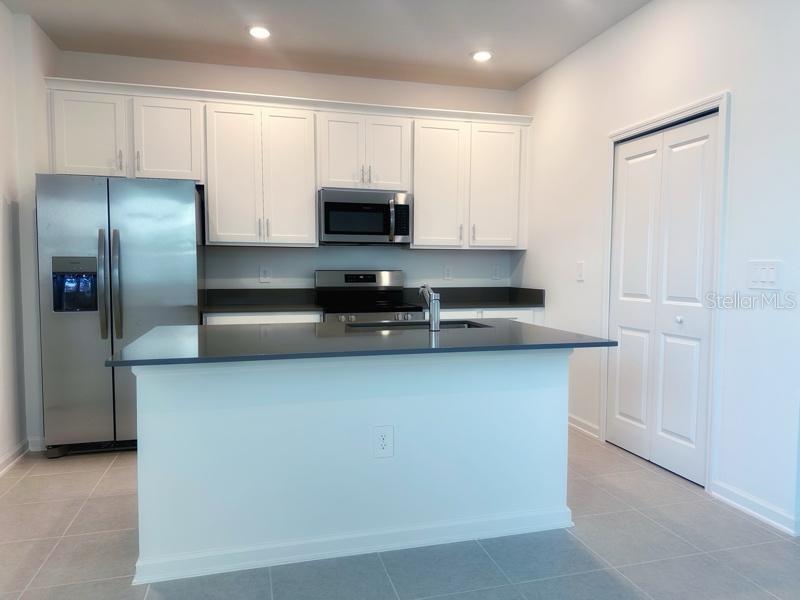 A kitchen features white cabinets, stainless steel appliances, a dark countertop, and a center island — 2639 CANDIED APPLE ALLEY, KISSIMMEE, FL