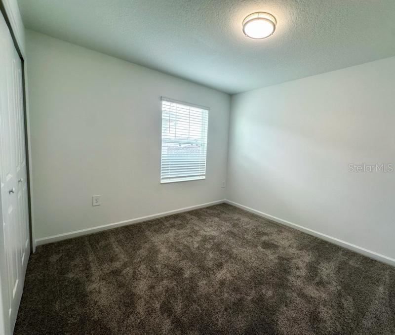 An empty bedroom features gray carpet, white walls, a single window, and a closet door — 2639 CANDIED APPLE ALLEY, KISSIMMEE, FL