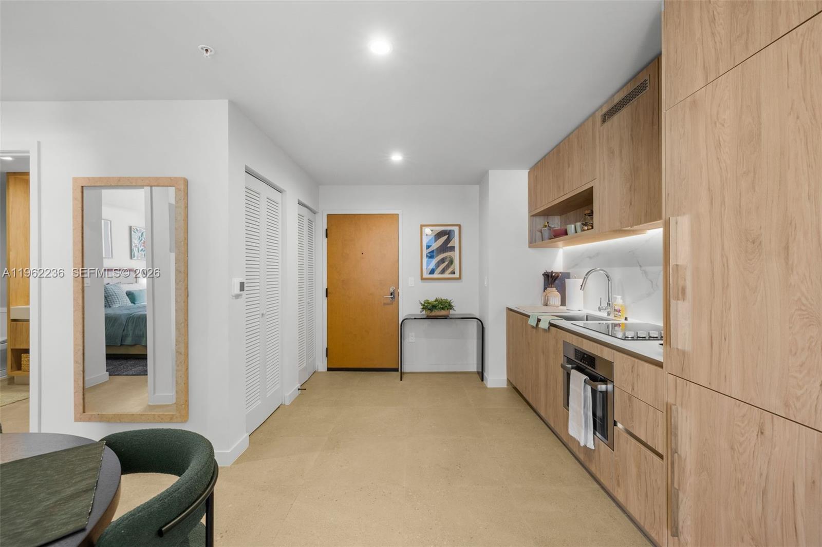A modern kitchen features light wood cabinetry, a stainless steel oven, and a neutral floor — 11 NE 6th St # 1611, Miami FL 33132, MIAMI, FL