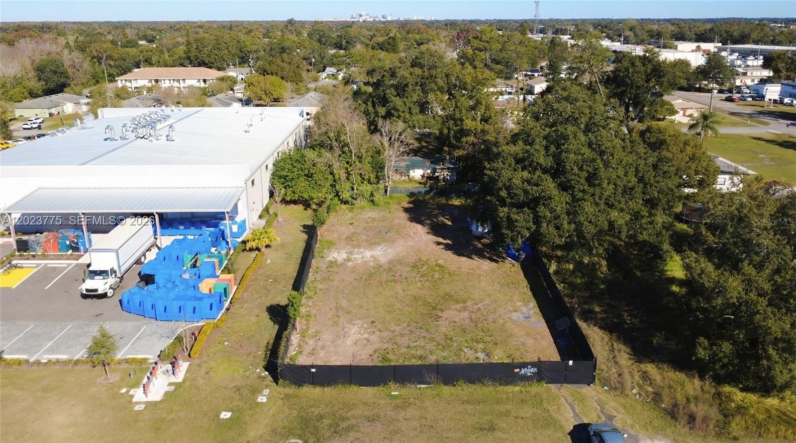 An aerial view shows a vacant, fenced-in rectangular lot adjacent to a large industrial building — 303 E LANCASTER, Orlando FL 32809, ORLANDO, FL