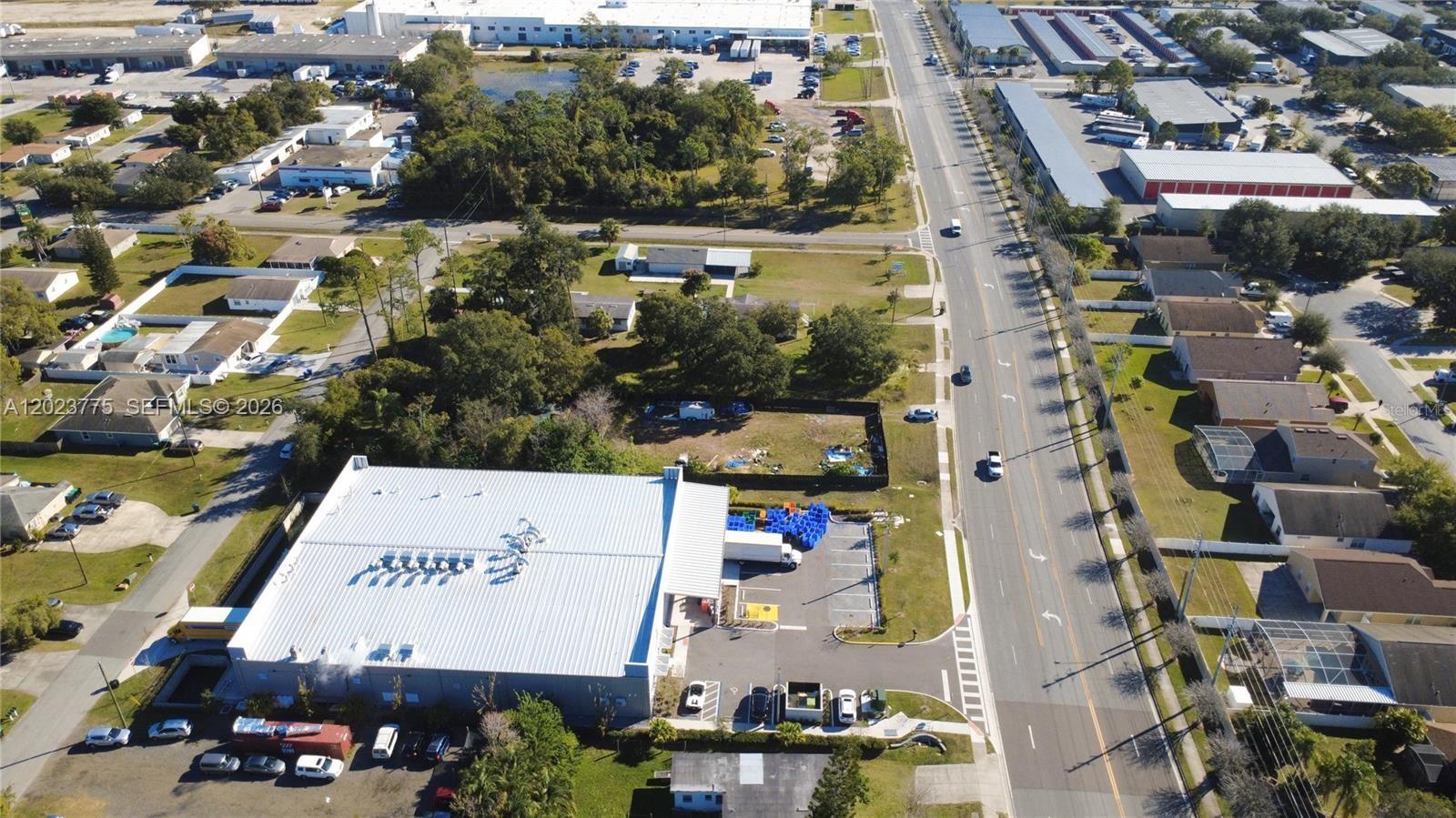 An aerial view shows a large commercial building with a parking lot beside a road — 303 E LANCASTER, Orlando FL 32809, ORLANDO, FL