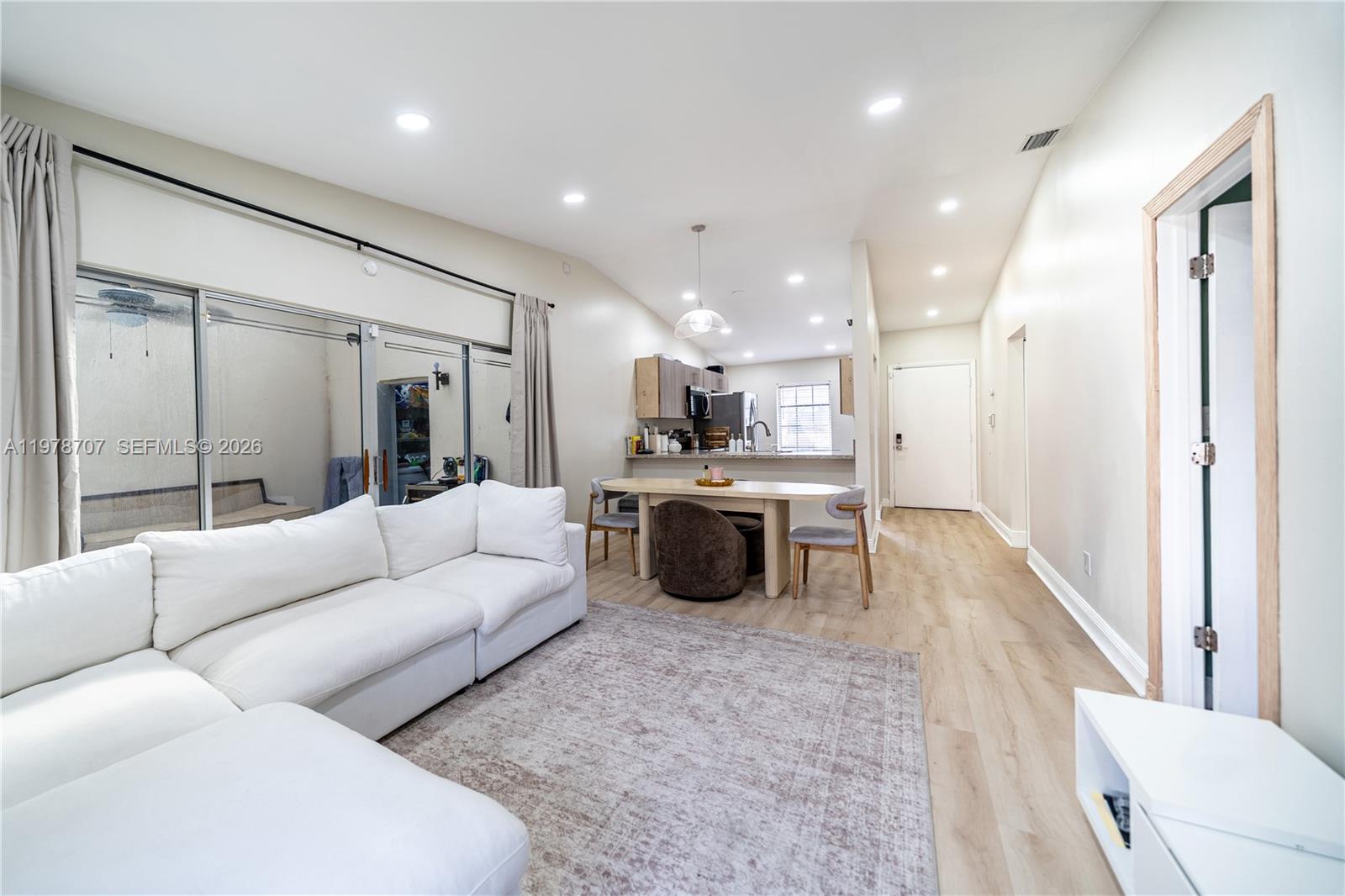 A living room with a white sectional sofa, dining area, and kitchen in an open layout — 9341 E Fern Ln, Miramar FL 33025, MIRAMAR, FL