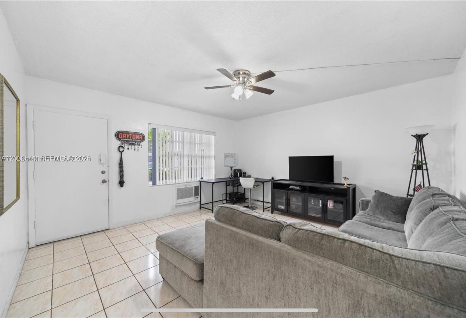 A living room features a gray sectional sofa, a television console, and a desk area — 16900 NE 14 # 109, Miami FL 33162, MIAMI, FL