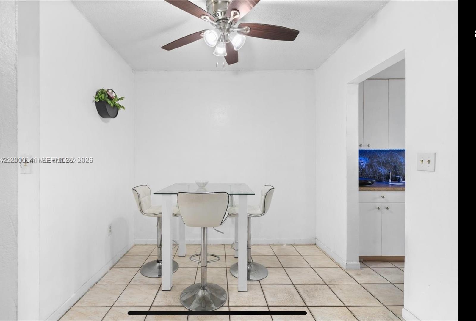 A dining area with a glass-top table, three bar stools, and tile flooring — 16900 NE 14 # 109, Miami FL 33162, MIAMI, FL