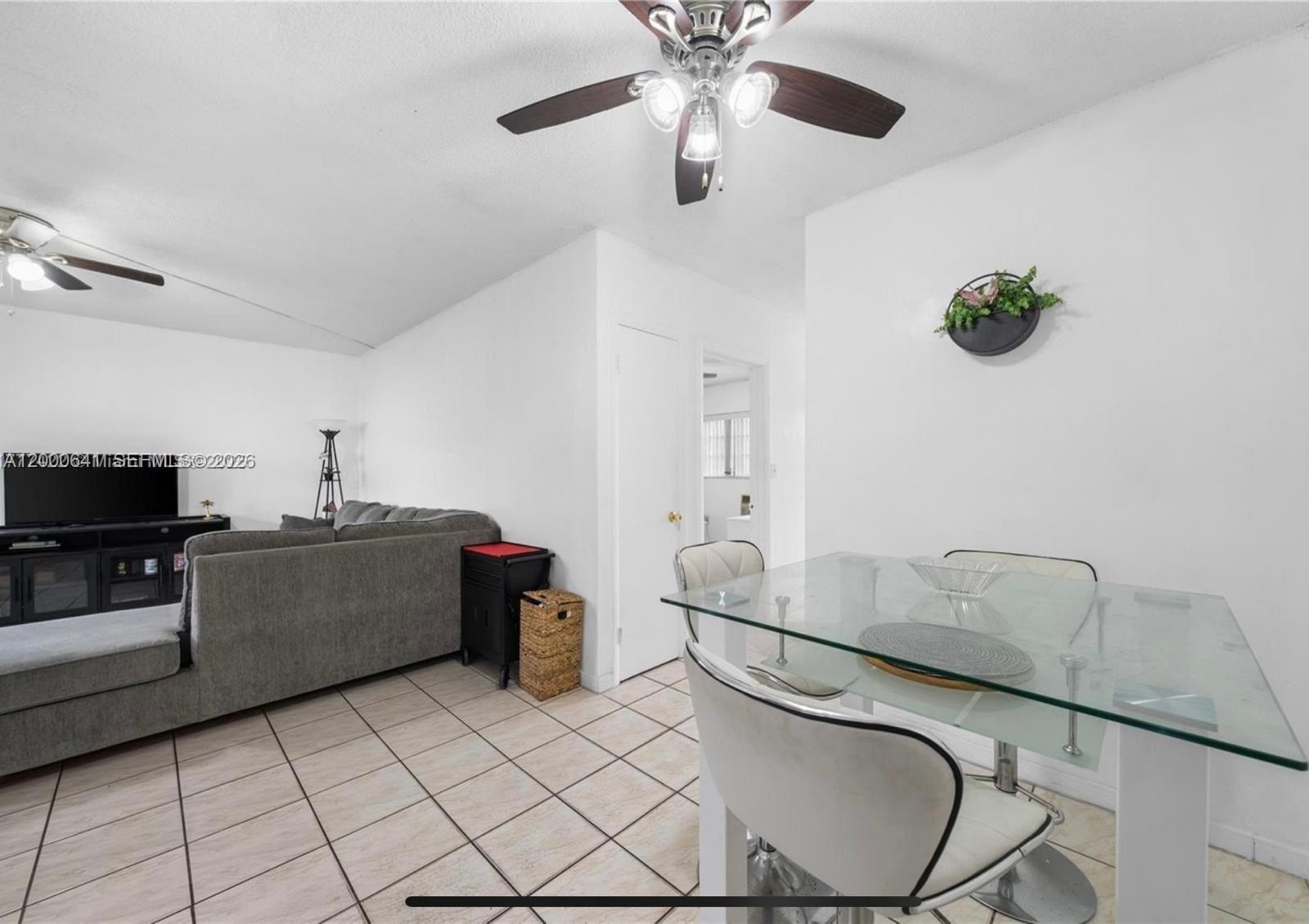 A dining area with a glass table and tile floors opens into a living room — 16900 NE 14 # 109, Miami FL 33162, MIAMI, FL