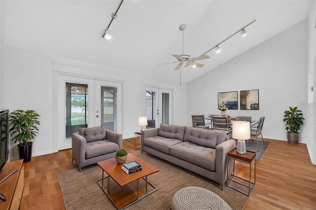 A living and dining room with vaulted ceilings, track lighting, and hardwood floors — 1502 BUCKEYE ROAD NE UNIT 4, WINTER HAVEN, FL