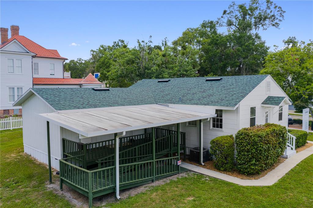 An exterior view of a white building with a green shingled roof and a ramp — 14721 MAIN STREET, ALACHUA, FL