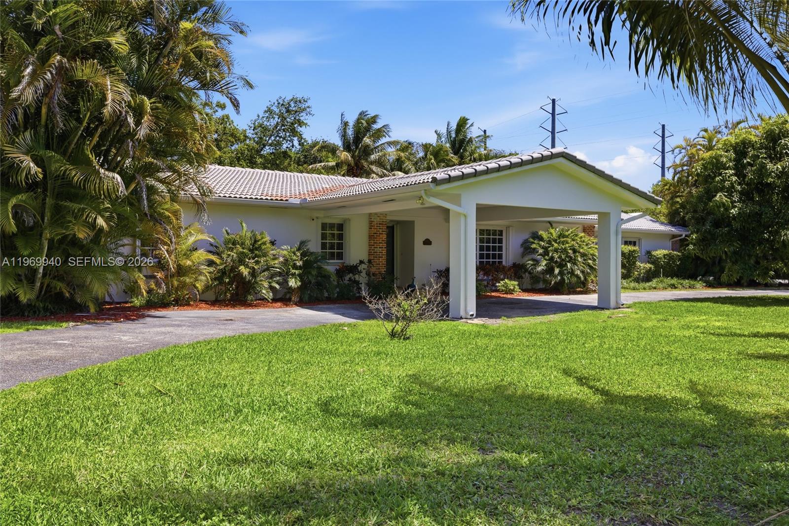 A white single-story house features a covered entryway, a tiled roof, and a paved driveway — 14721 SW 67th Ave, Coral Gables FL 33158, CORAL GABLES, FL
