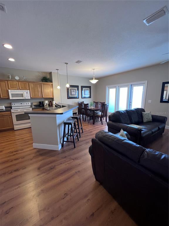 An open-concept kitchen with a breakfast bar overlooks a dining area and living room — 221 3RD AVENUE E UNIT F-102, HORSESHOE BEACH, FL