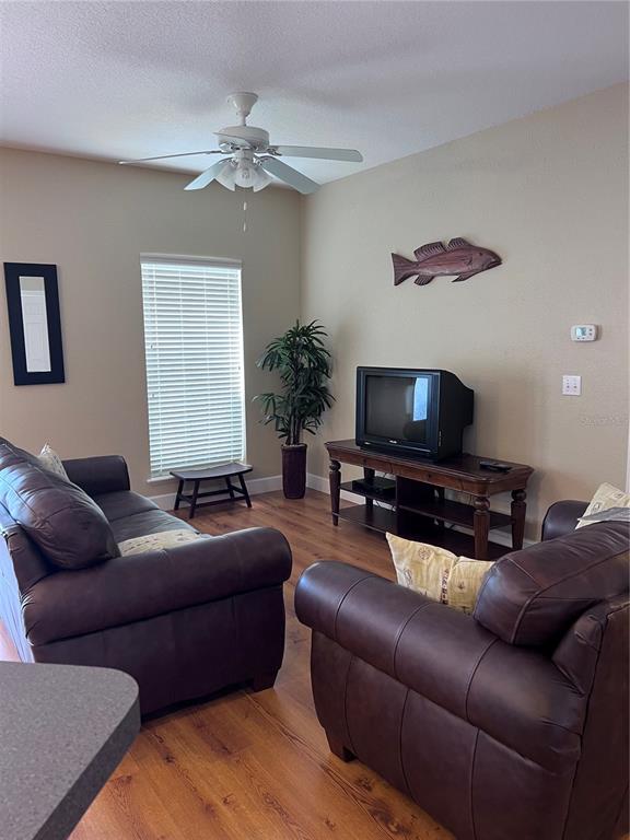 A living room features brown leather furniture, a television on a wooden stand, and wood flooring — 221 3RD AVENUE E UNIT F-102, HORSESHOE BEACH, FL