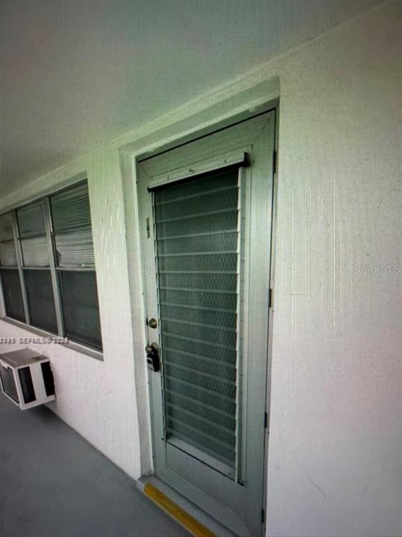 A white exterior wall features a window, a window air conditioner, and a screen door — 163 COVENTRY G UNIT 163, WEST PALM BEACH, FL