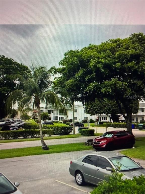 A view of a parking lot with cars, a palm tree, and apartment buildings — 163 COVENTRY G UNIT 163, WEST PALM BEACH, FL