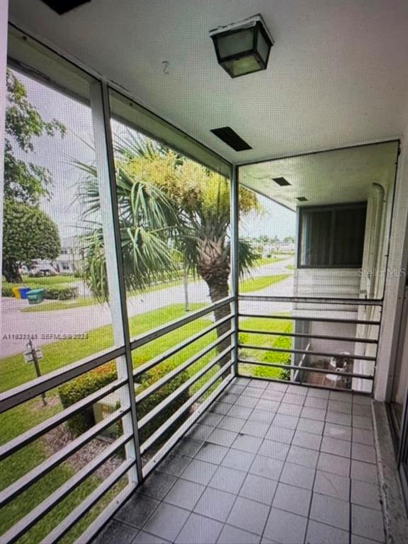 A screened-in balcony features tiled flooring, a ceiling light, and views of a palm tree — 163 COVENTRY G UNIT 163, WEST PALM BEACH, FL