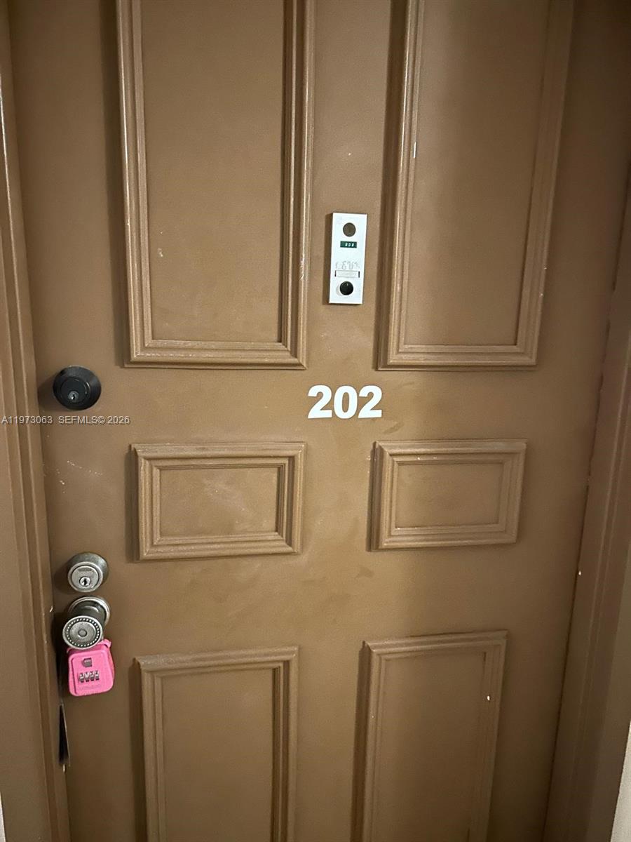 A brown apartment door labeled 202 features a lockbox and a doorbell — 3821 Environ Blvd # 202, Lauderhill FL 33319, LAUDERHILL, FL