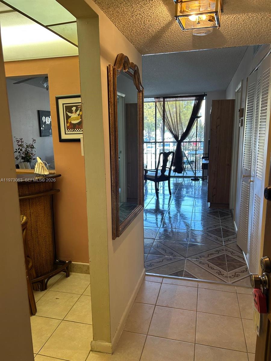 An entryway leads to a tiled living area with a balcony and a wall mirror — 3821 Environ Blvd # 202, Lauderhill FL 33319, LAUDERHILL, FL